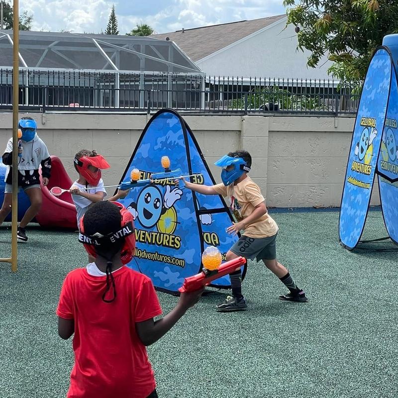 Children play gellyball around pop-up bunkers on a playground