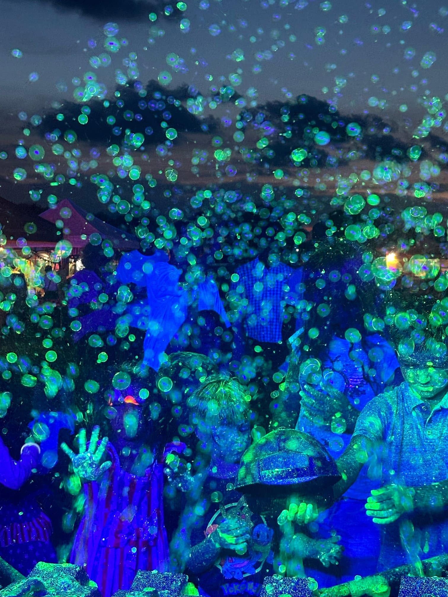 glow-in-the-dark bubbles filling the air over a crowd at night