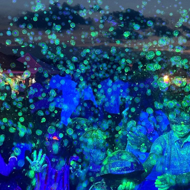 glow-in-the-dark bubbles filling the air over a crowd at night