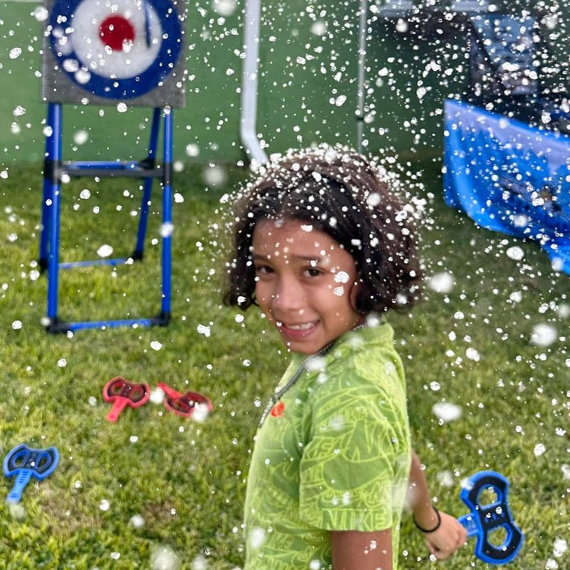 A boy covered in snow holds a soft throwing axe in front of the target