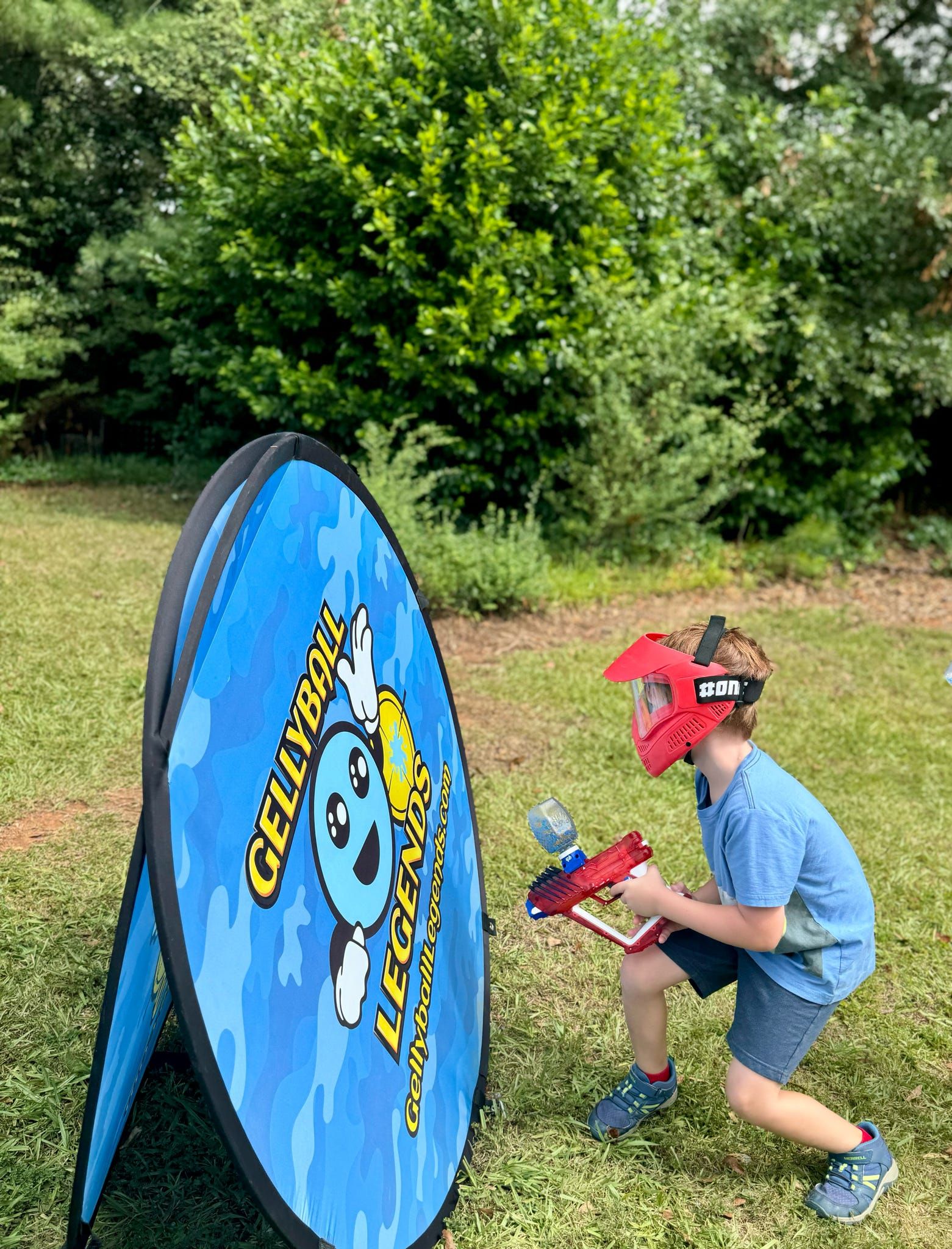 A boy in a red mask crouches beside a round pop-up bunker