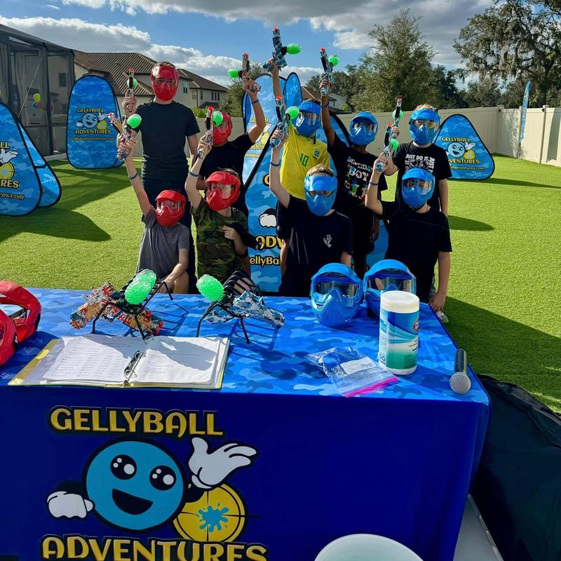 Kids raise their gel blasters behind the check-in table