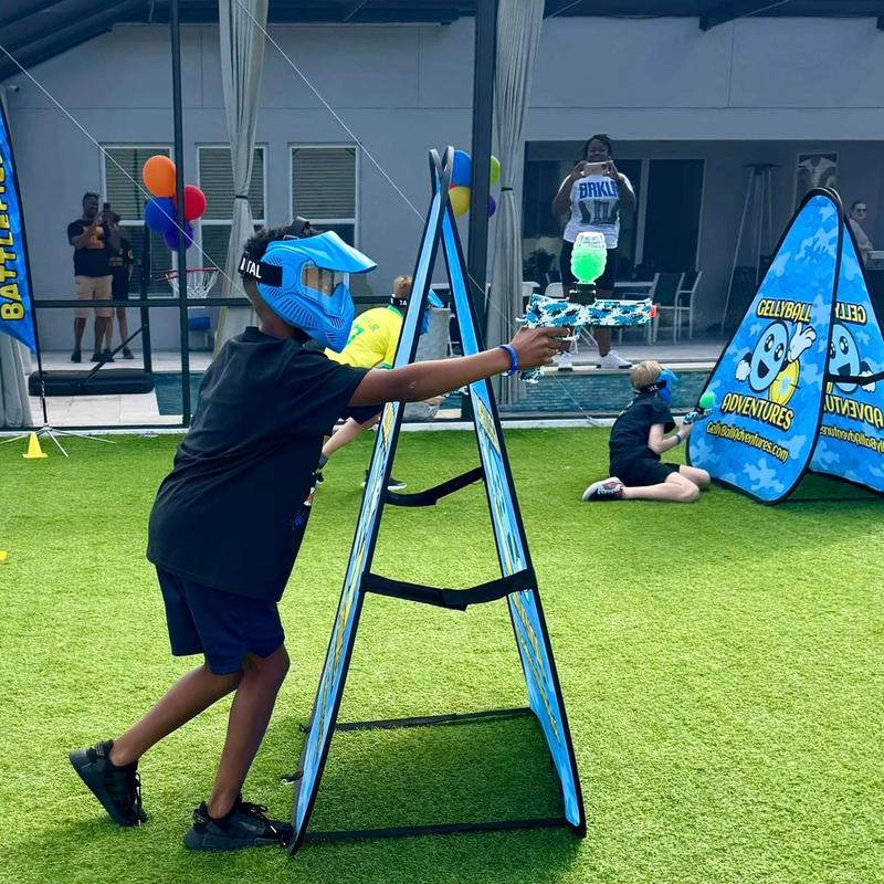 A boy in a mask aims around an A-frame bunker at a backyard birthday party