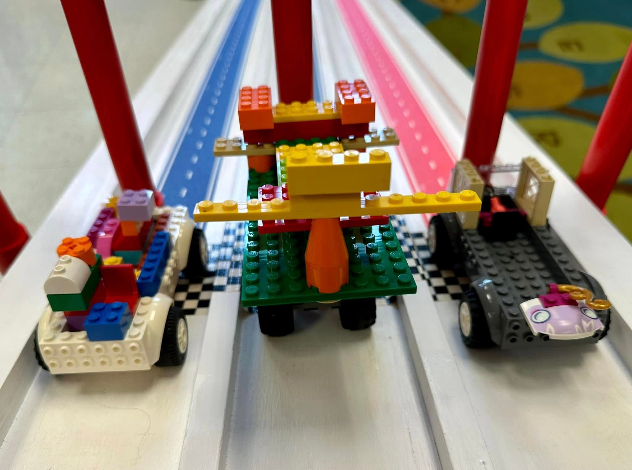 Three brick-built cars wait at the start gate of the Derby ramp's striped lanes