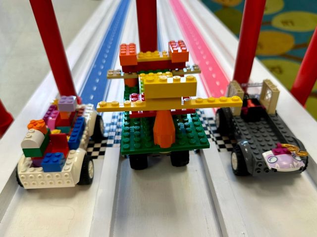 Three brick-built cars wait at the start gate of the Derby ramp's striped lanes