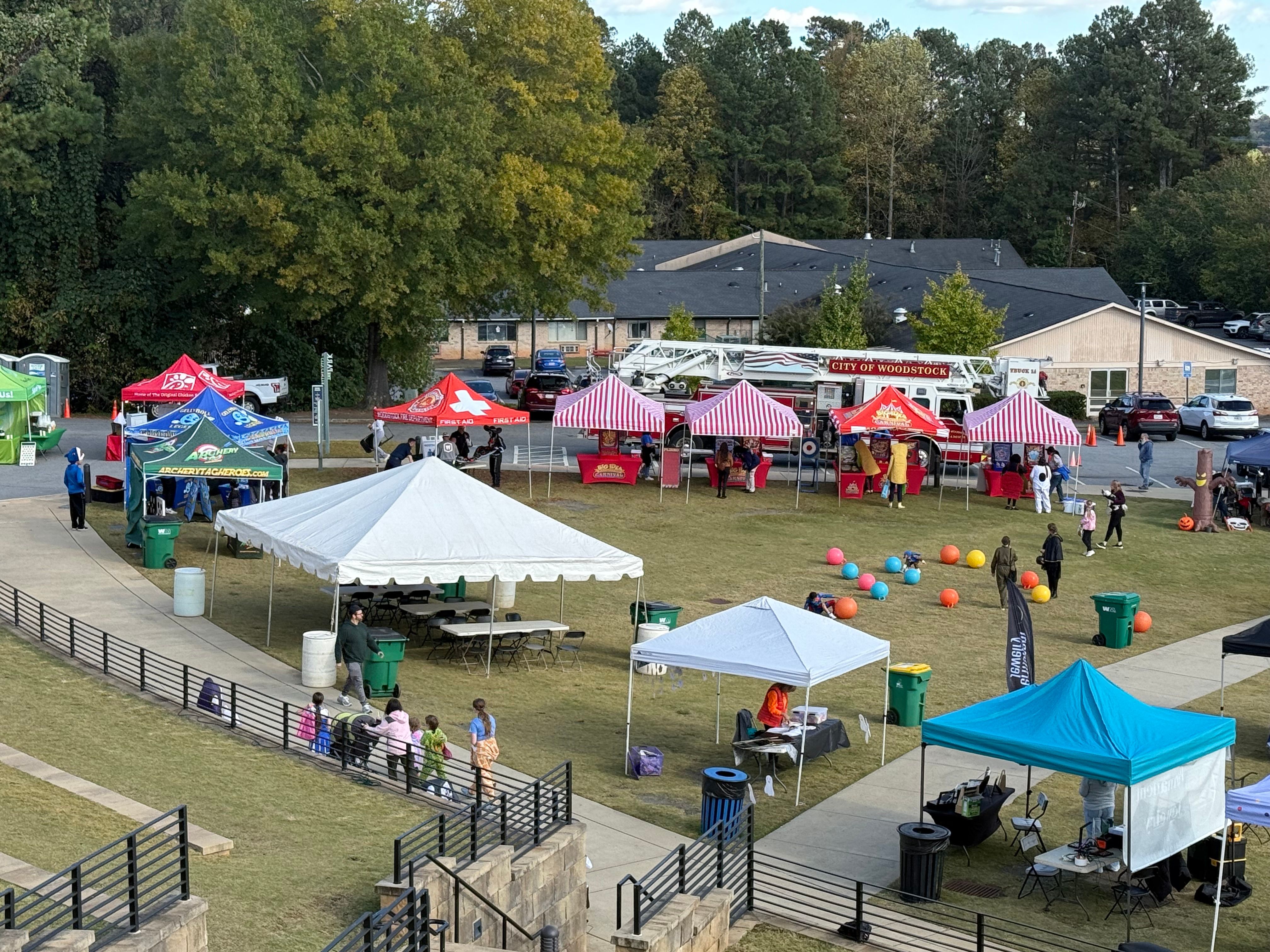 several red and white striped tents and carnival games setup for a community Halloween festival