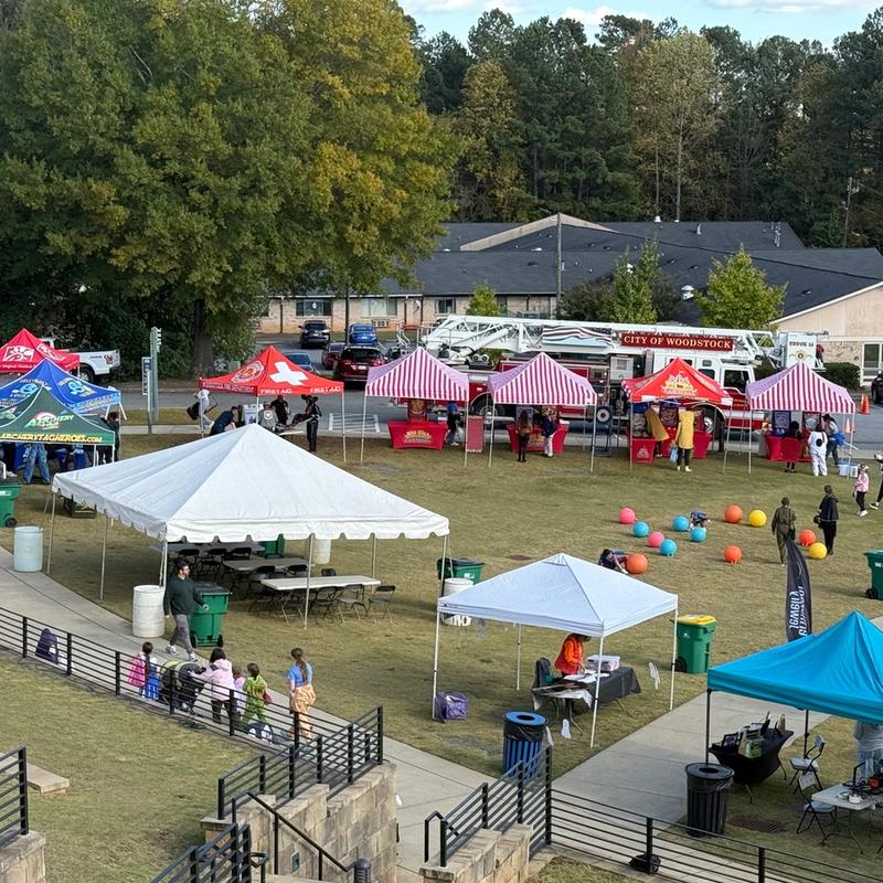 several red and white striped tents and carnival games setup for a community Halloween festival