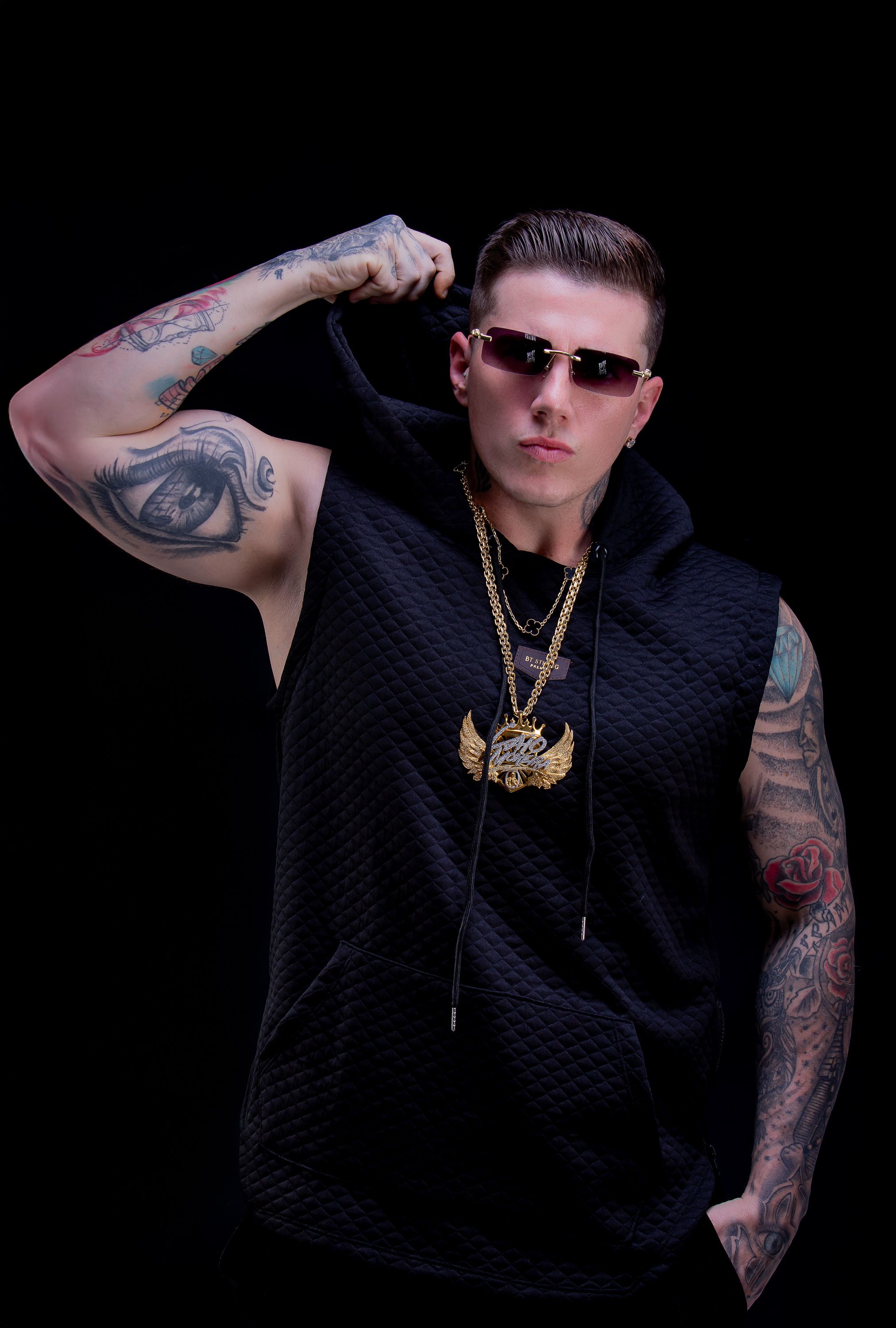 DJ Caio Moreira com regata preta e braço tatuado erguido