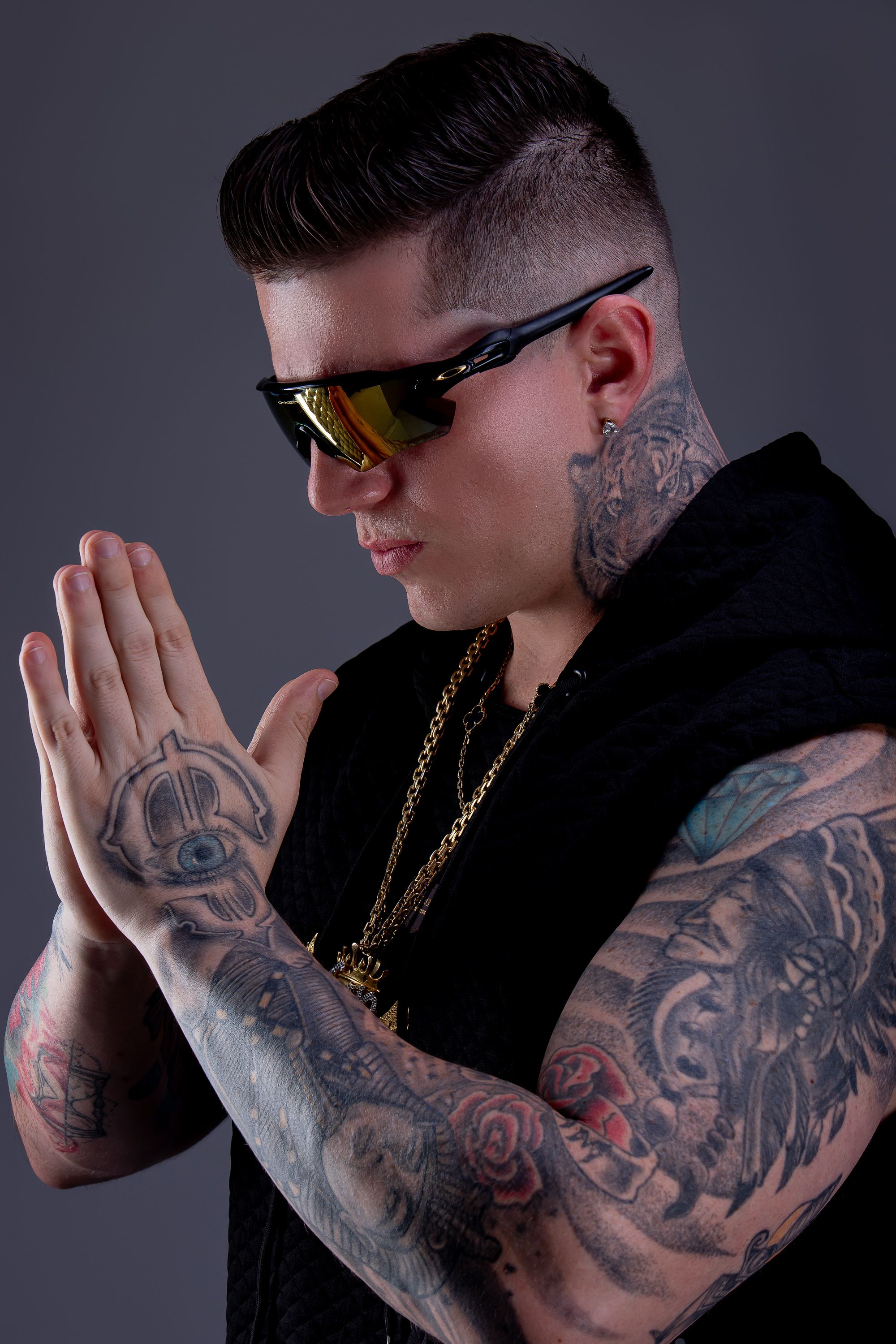 DJ Caio Moreira com as mãos unidas e braços tatuados