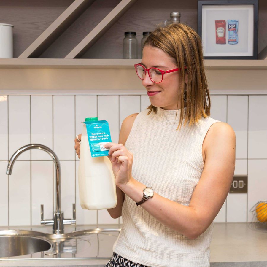Woman holding milk bottle with Mimica label