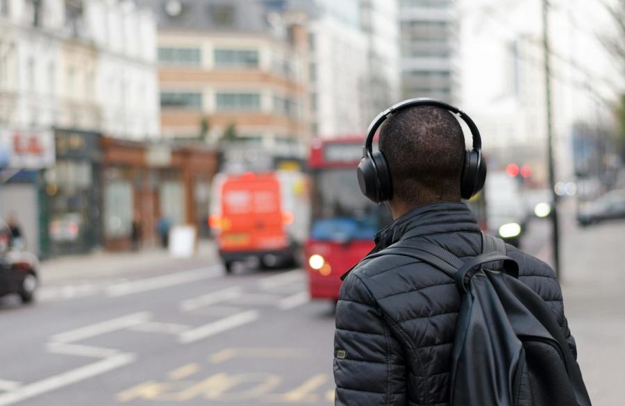 male listening to podcast on busy road