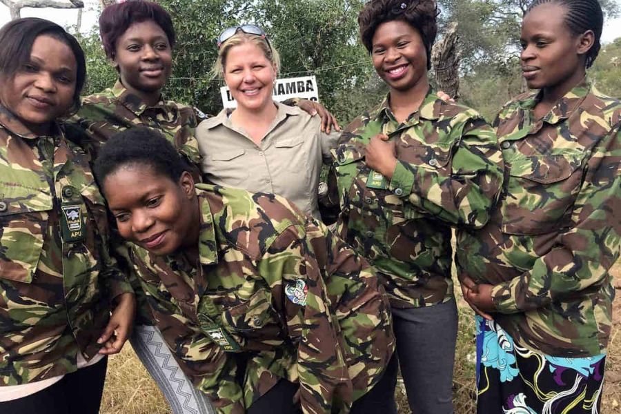 Holly Budge stands outside with members of the Black Mambas female rangers, who wear camouflage jackets.