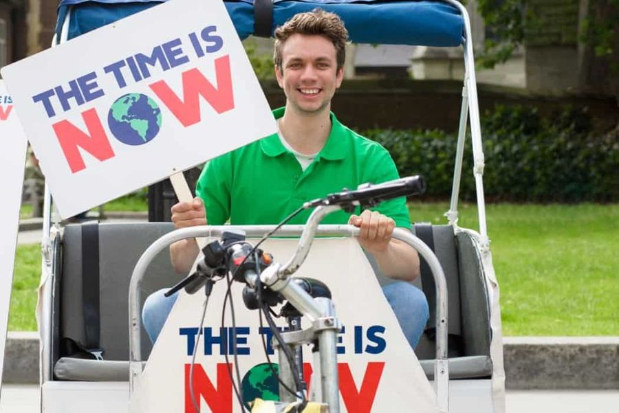 Young man holding sign that reads The Time Is Now
