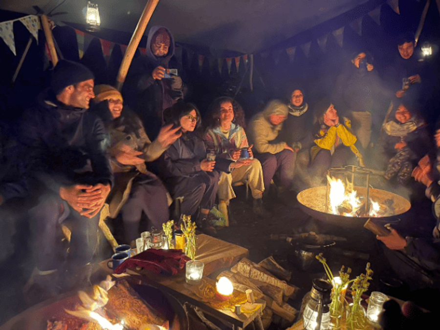 People from diverse ethnic backgrounds gathering outdoors around a fire.