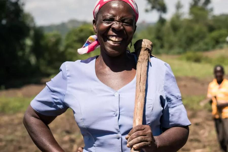 A female smallholder farmer from in Sub-Saharan Africa smiling into the camera