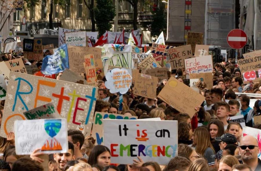Crowd of people at a protest holding signs about the climate crisis