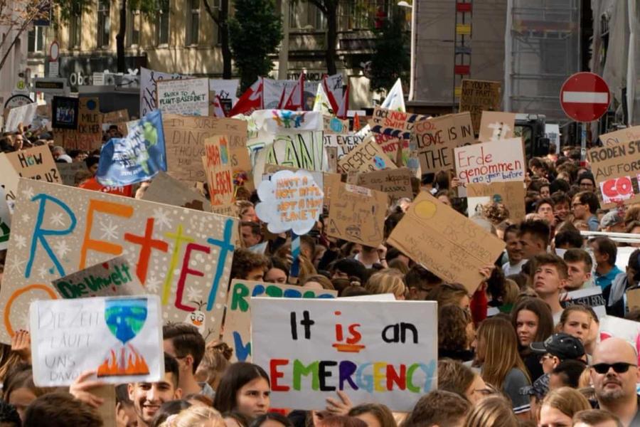 Crowd of people at a protest holding signs about the climate crisis