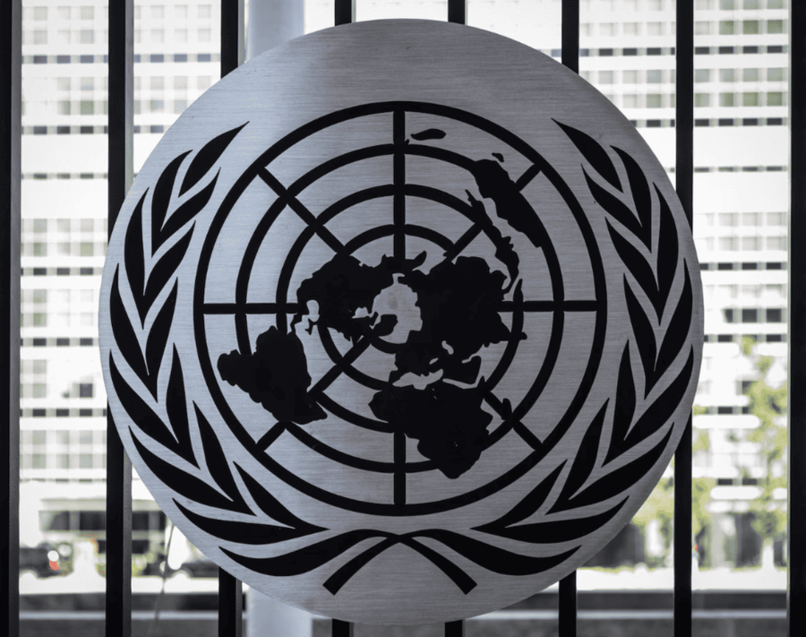 UN logo on a round metal piece on what looks like a metal door or fence