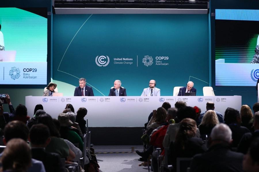 Five tips to supercharge your communications at COP29. Image shows a panel of 5 individuals, with and audience in the foreground. Behind the panelists are the COP29 and United Nations logos.