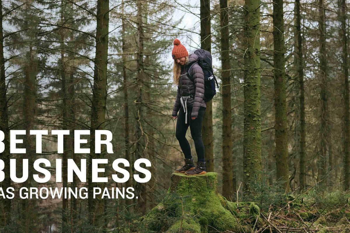 Person stood on a mossy tree stump in a wood. They're wearing Vivobarefoot shoes, a bobble hat and a rucksack. Text reads "Better business has growing pains."