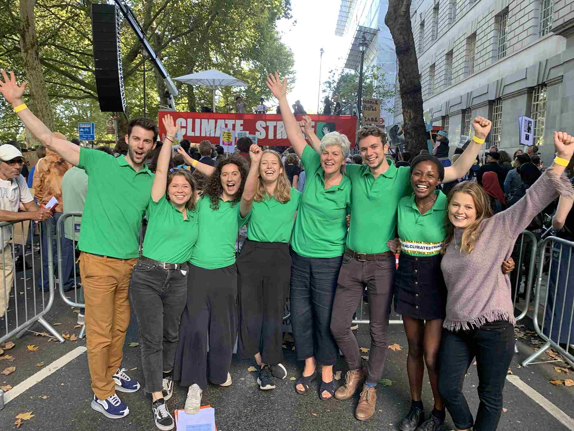A group of people in green t-shirts stand cheering at the camera
