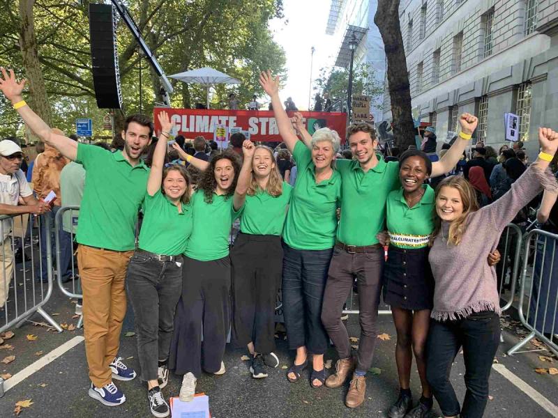 A group of people in green t-shirts stand cheering at the camera