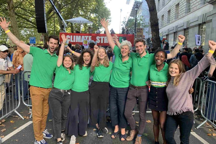 A group of people in green t-shirts stand cheering at the camera