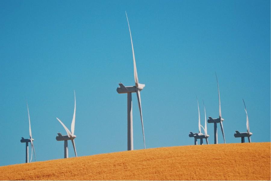 3 Common myths about renewable energy debunked. Image shows wind turbines in the foreground and a blue sky.
