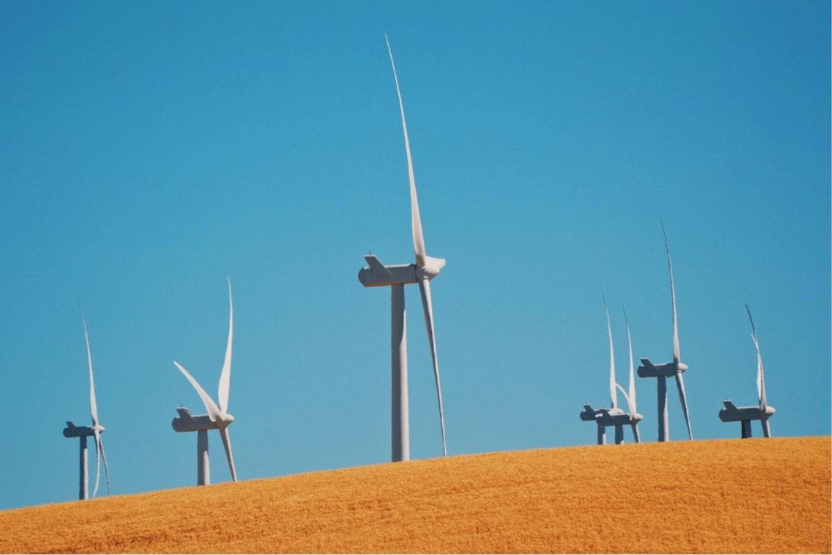 3 Common myths about renewable energy debunked. Image shows wind turbines in the foreground and a blue sky.