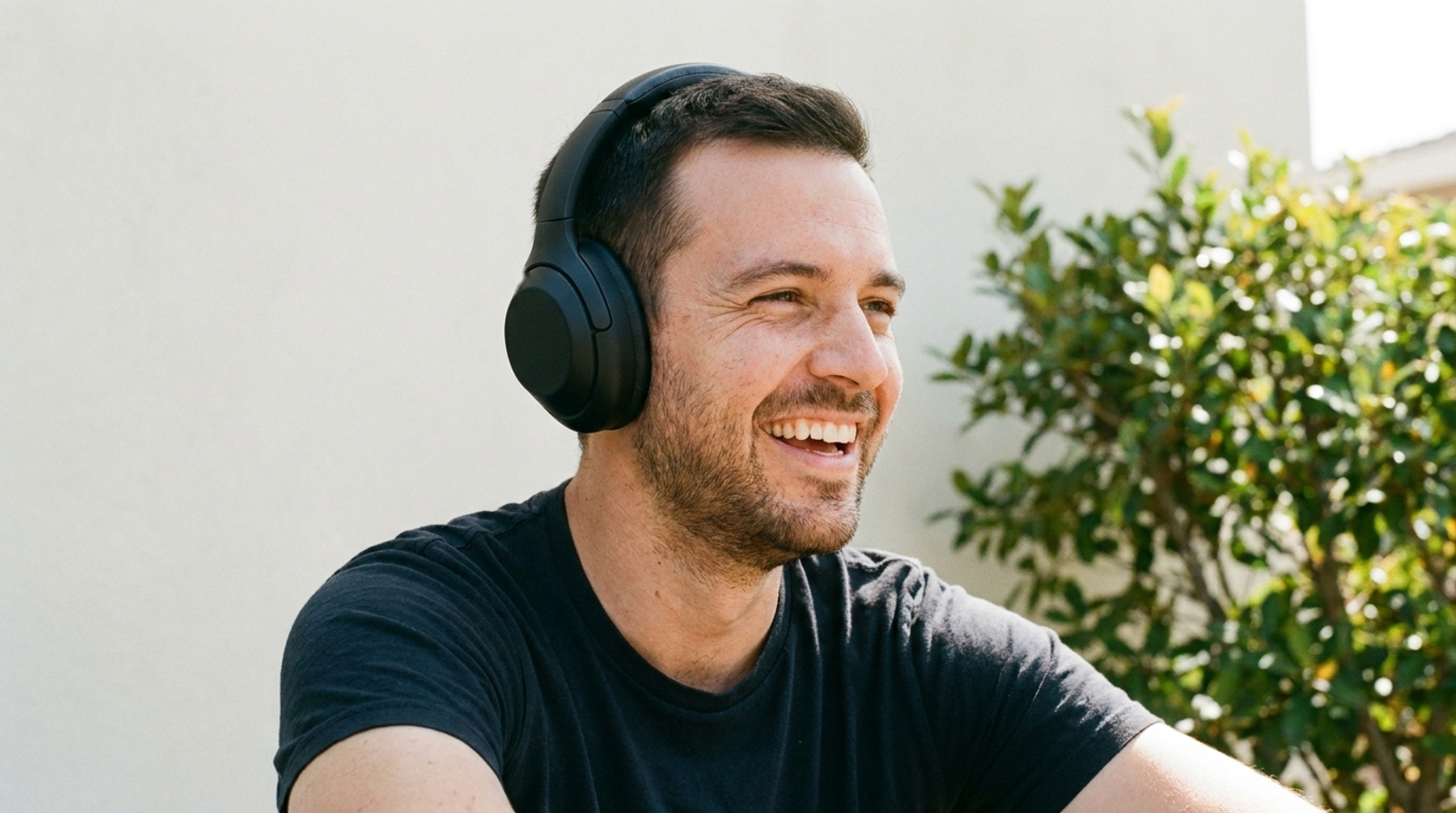 Un homme rit en pleine conversation, un casque audio sur les oreilles.