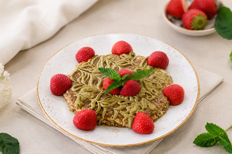 Pancake drizzled with pistachio cream and topped with fresh strawberries and mint