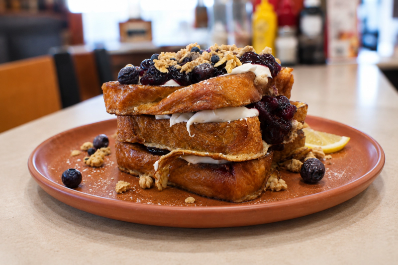 A stack of baklava French toast with blueberry compote on a diner counter