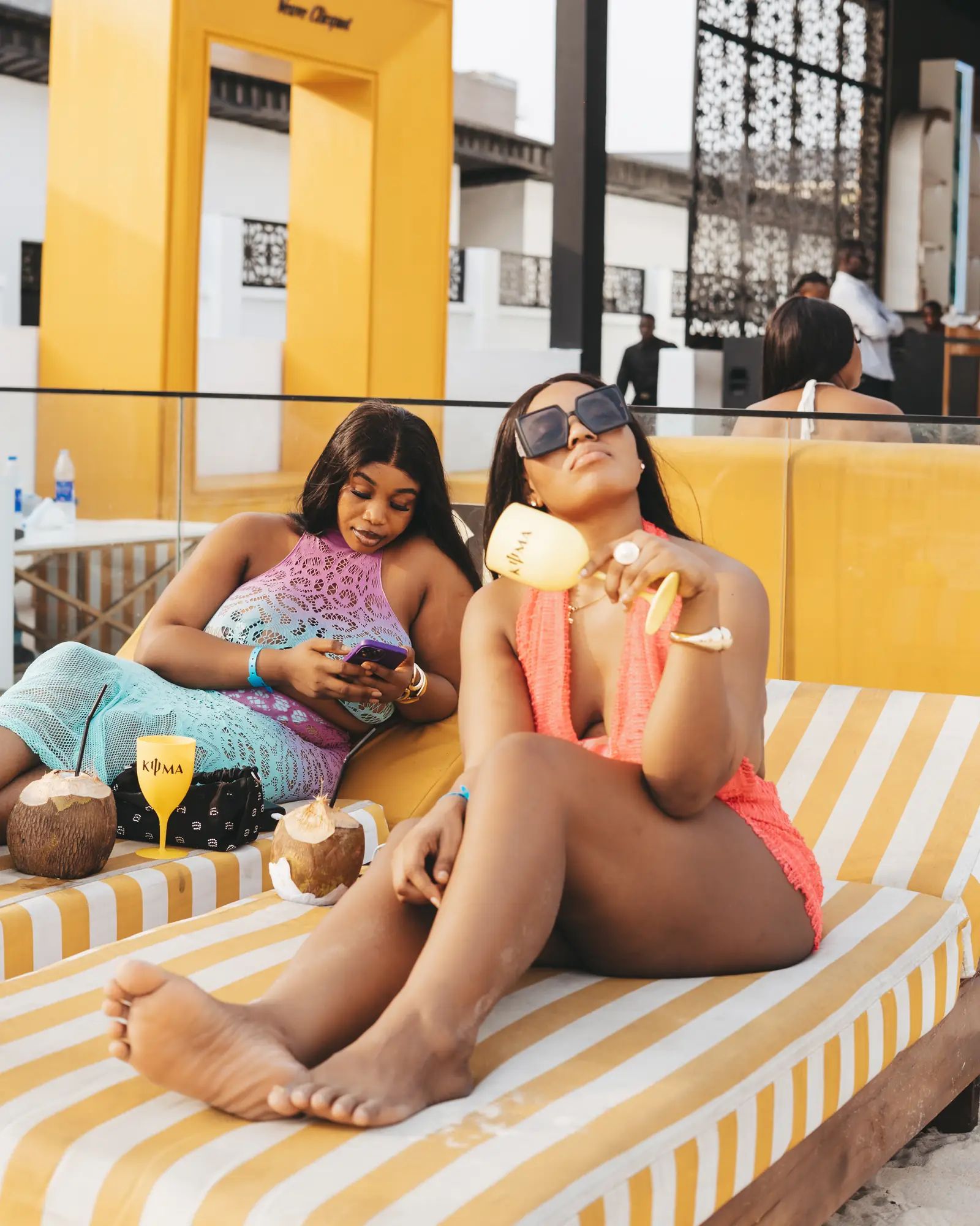 Two guests with drinks on a striped daybed