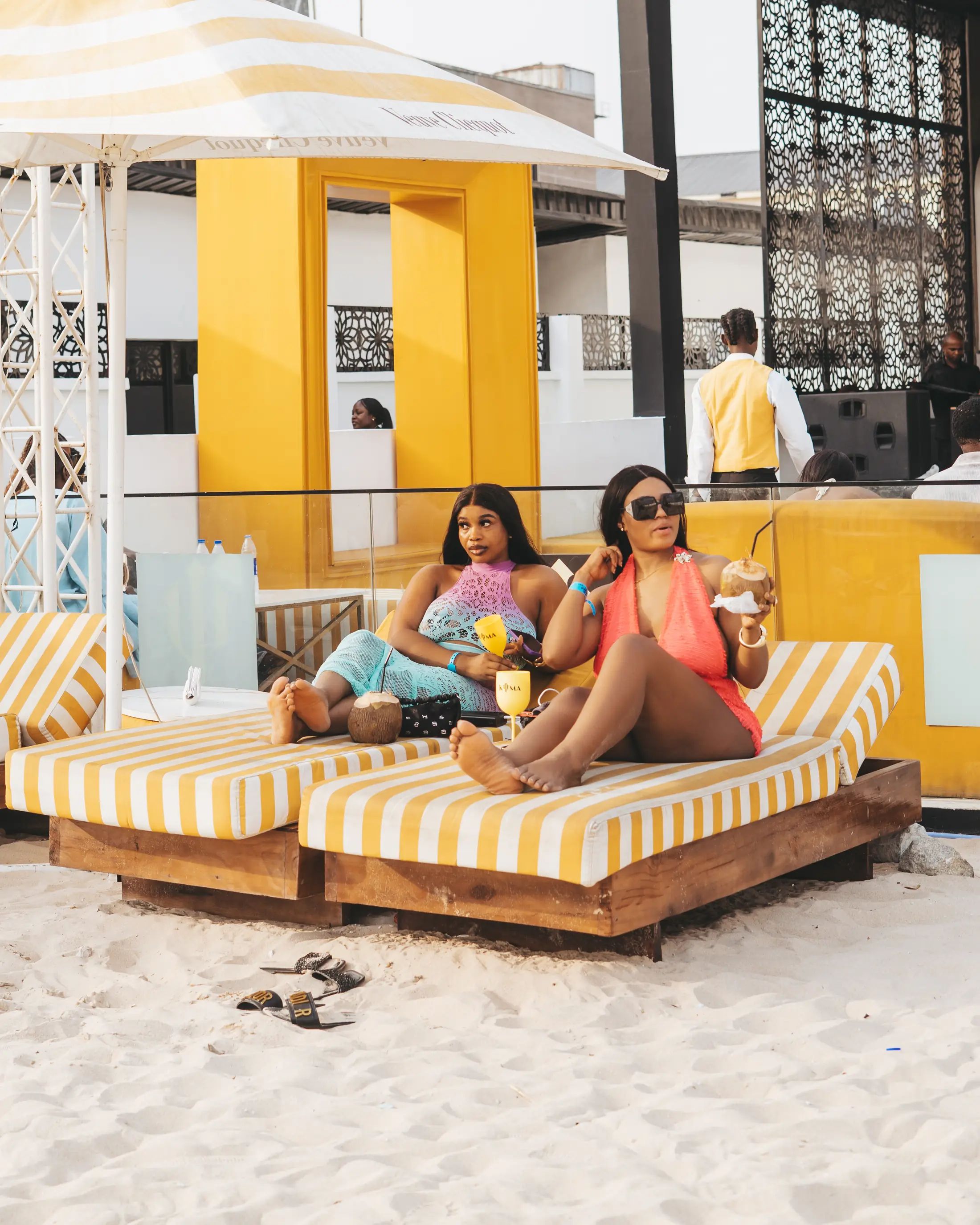 Guests on striped daybeds under a cabana