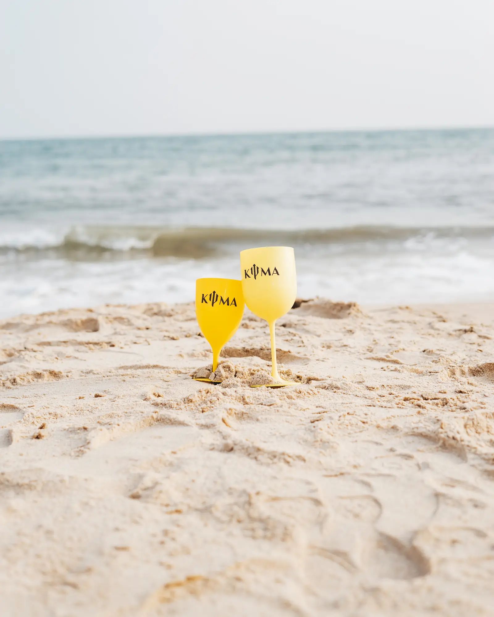 KYMA cups on the sand, sea behind