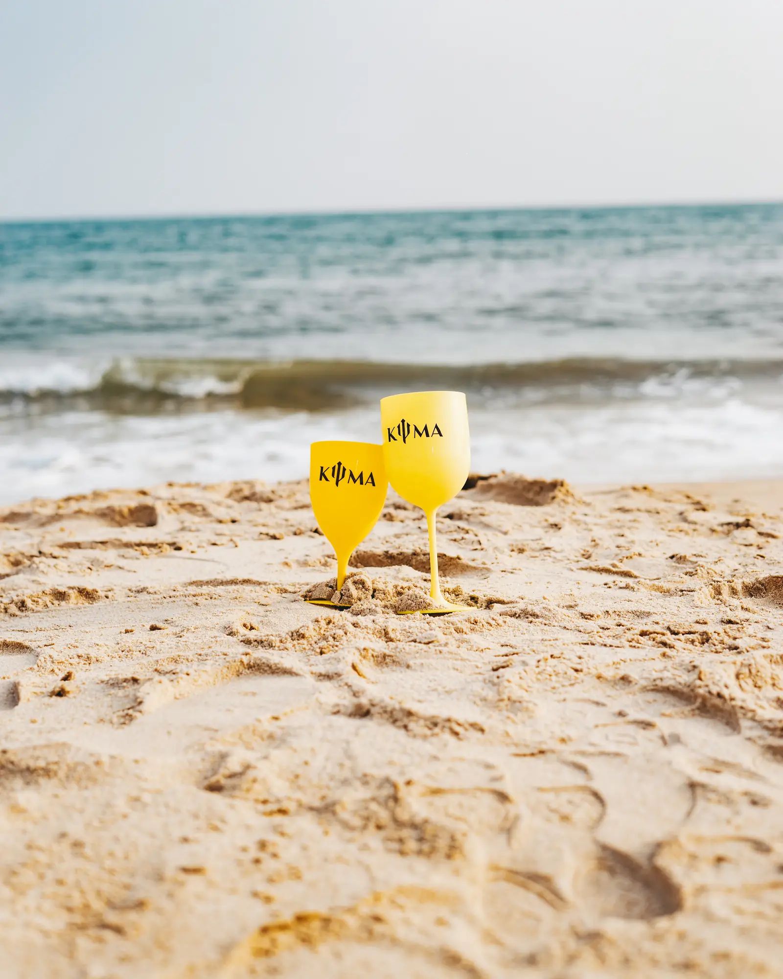 KYMA cups on the sand, sea behind
