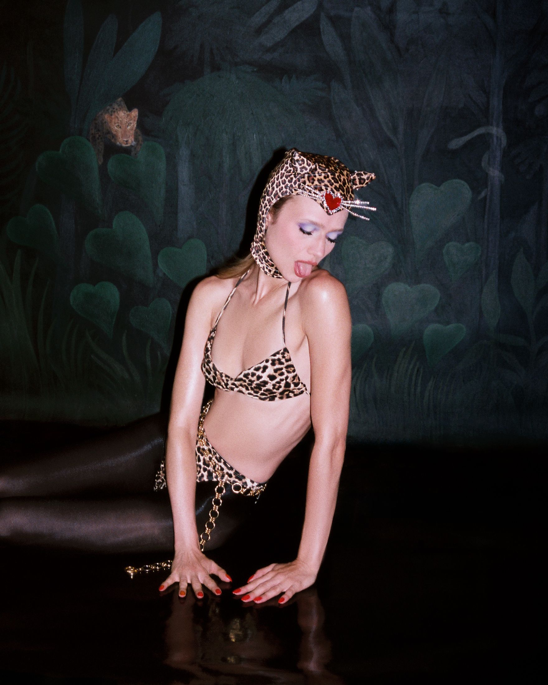 Model posing in leopard costume in front of jungle backdrop