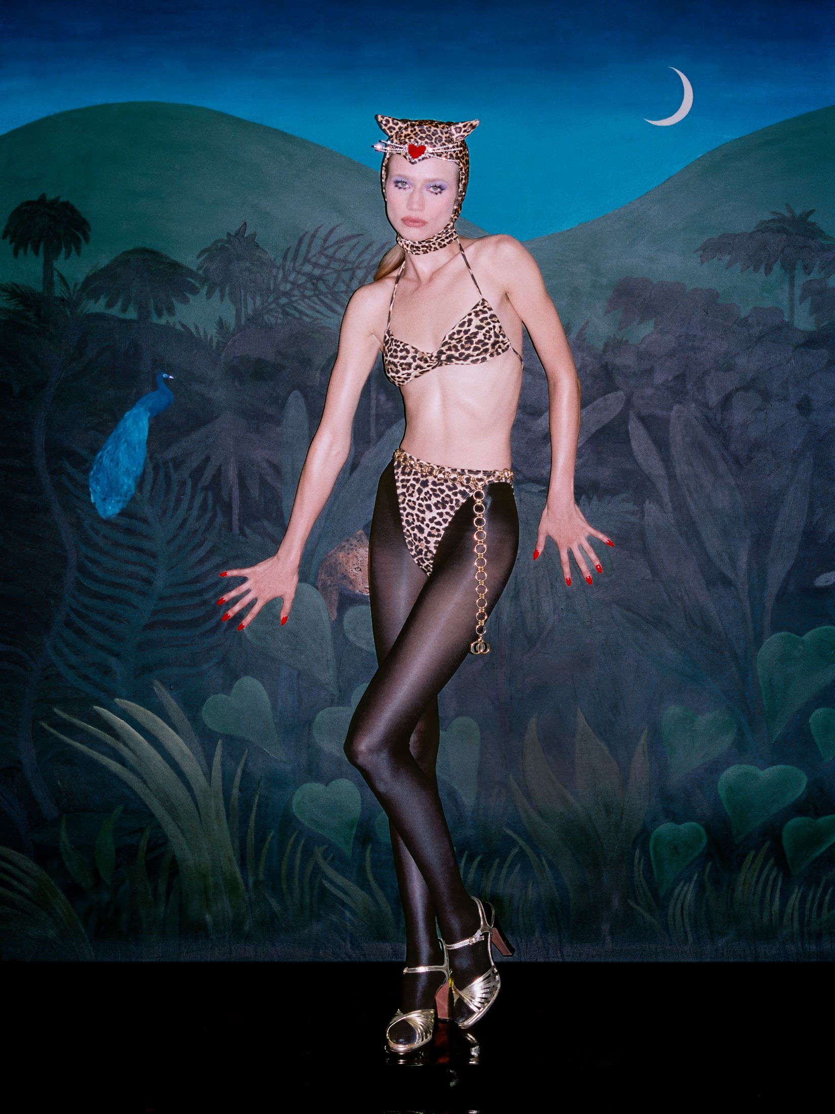 Model posing in leopard costume in front of jungle backdrop