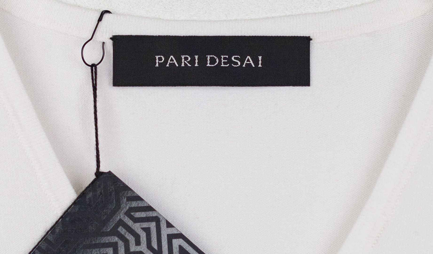 Clothing label on white knit sweater reading "Pari Desai"