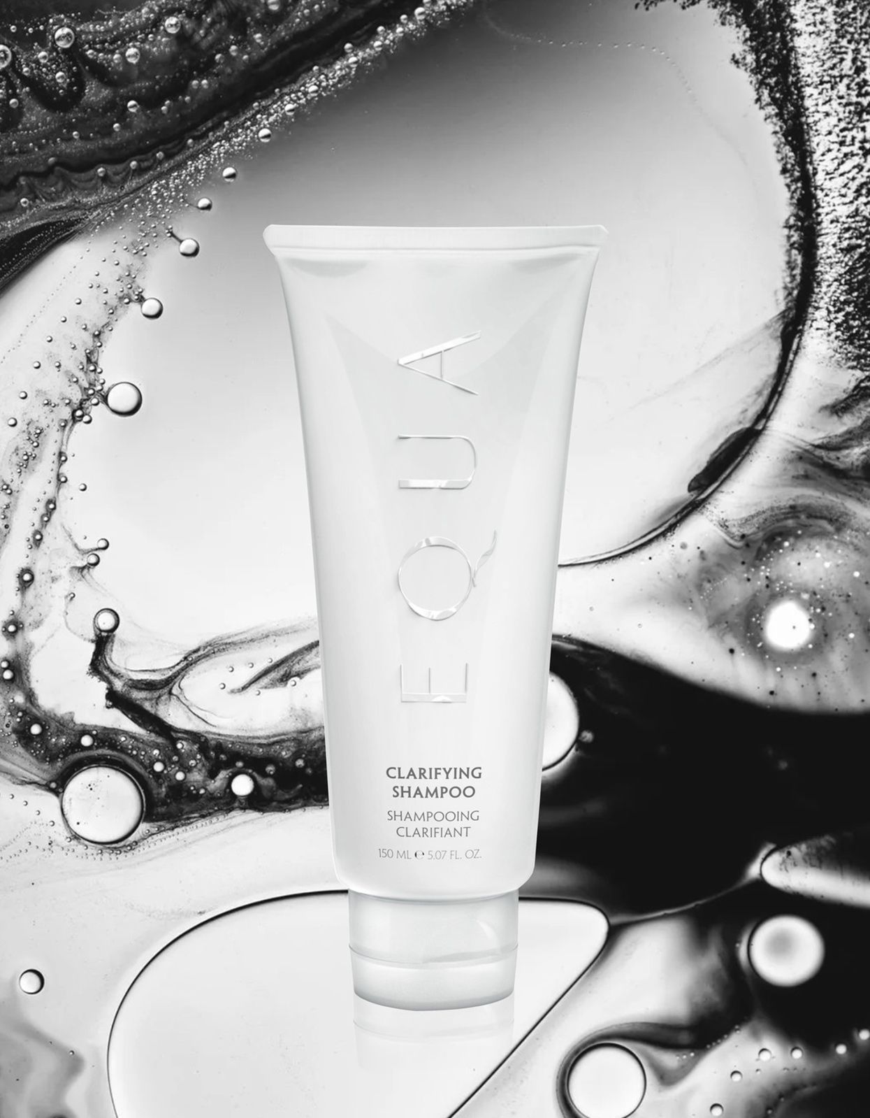 A tube of shampoo on a glass surface with a closeup detail of liquid splashing