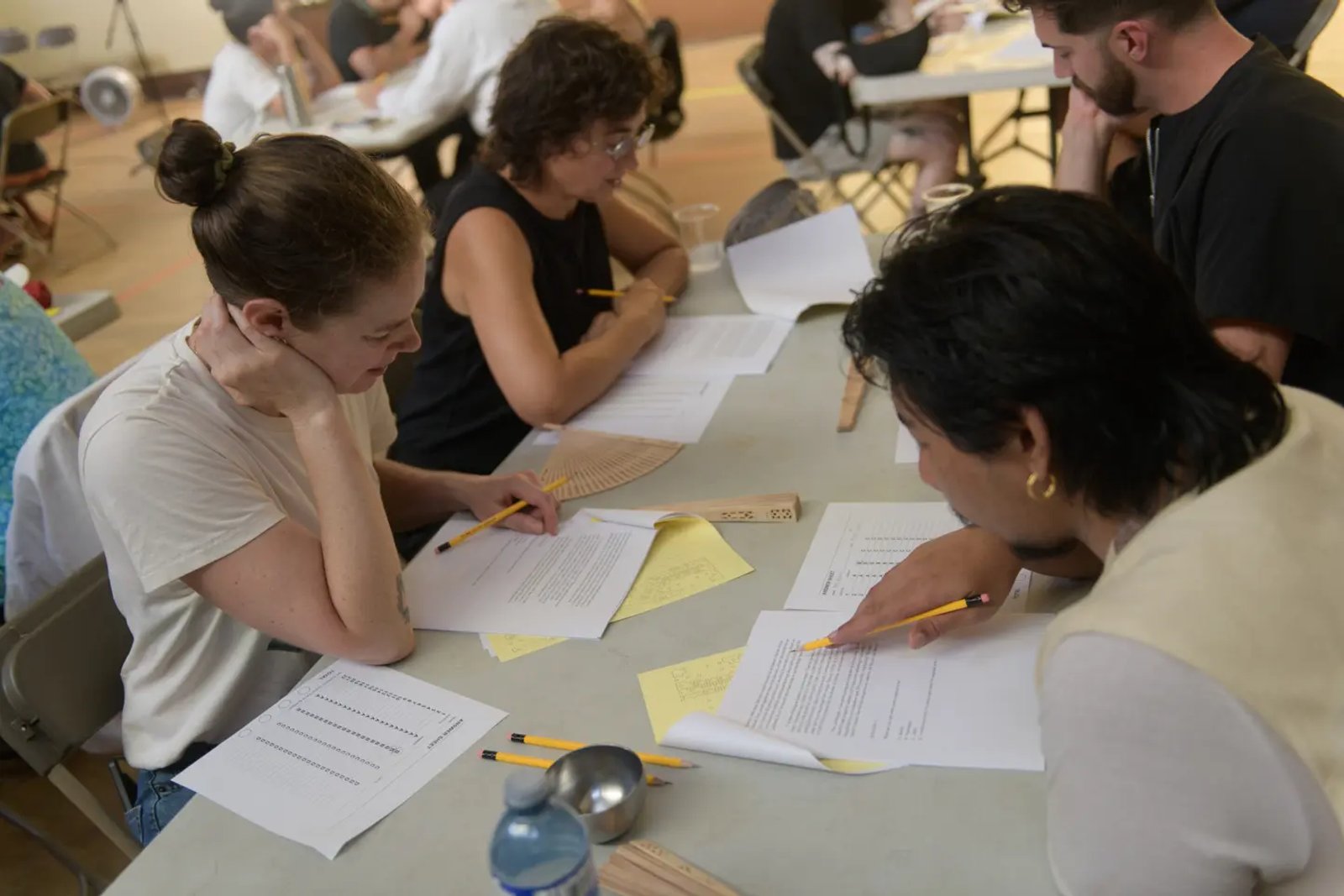 4 people around a desk, writing on papers