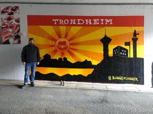 Graffiti artist Buggeklosser, standing in front of his painting at Sluppen. The painting is a stylisation of Trondheim in sunset