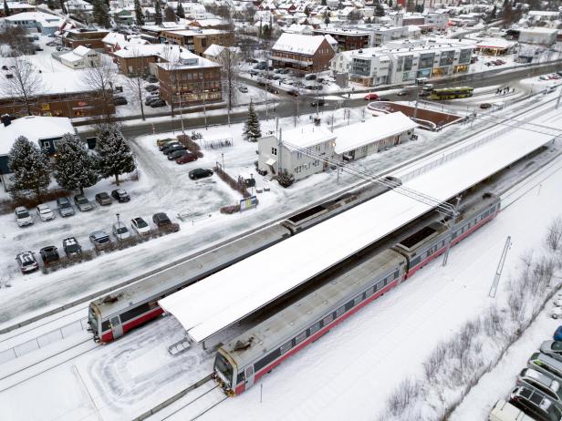 Two trains at a train station covered in snow. Its wintertime, but the weather is clear and nice.