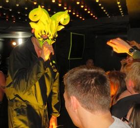 Man wearing mask singing into a microphone at a garage concert