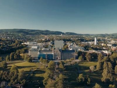Drone photo of NTNU Gløshaugen surrounded by greenery on a summers day.