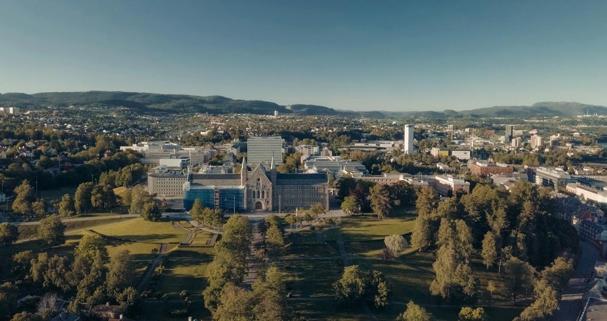 Drone photo of NTNU Gløshaugen surrounded by greenery on a summers day.