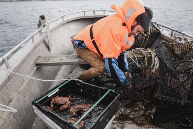 A crab fisher sitting in his both, untangling his gear. He has already gotten some crabs