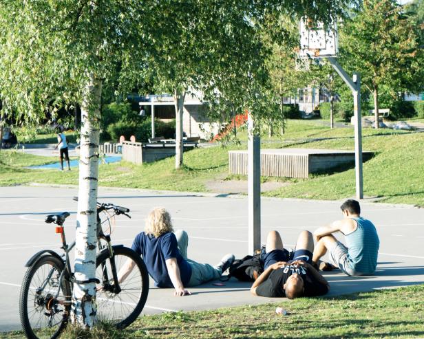 3 students chilling outside at a basketball court on a nice summer day