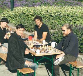 Four people gathered around two chess boards in a park in Trondheim