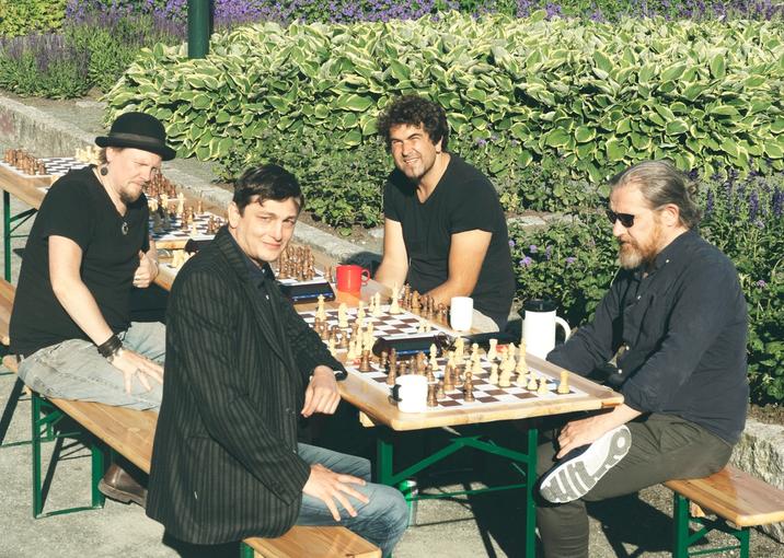 Four men playing chess in Ila parken on a sunny summer day.